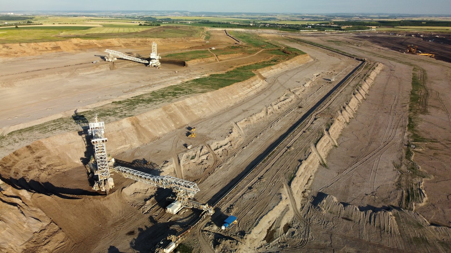 Large industrial machinery operates within a vast open-pit mine.